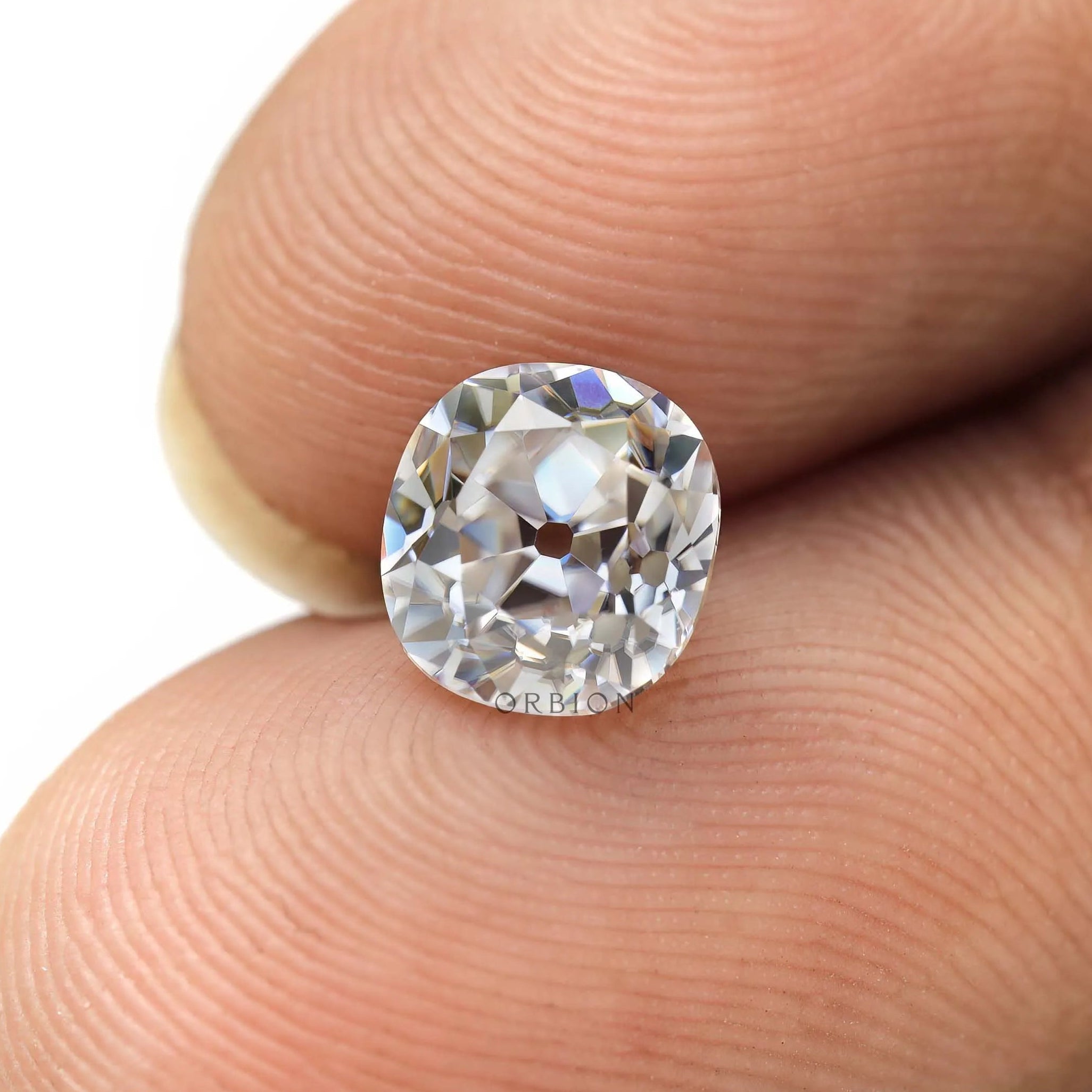 Elongated cushion loose moissanite displayed on fingertips for scale