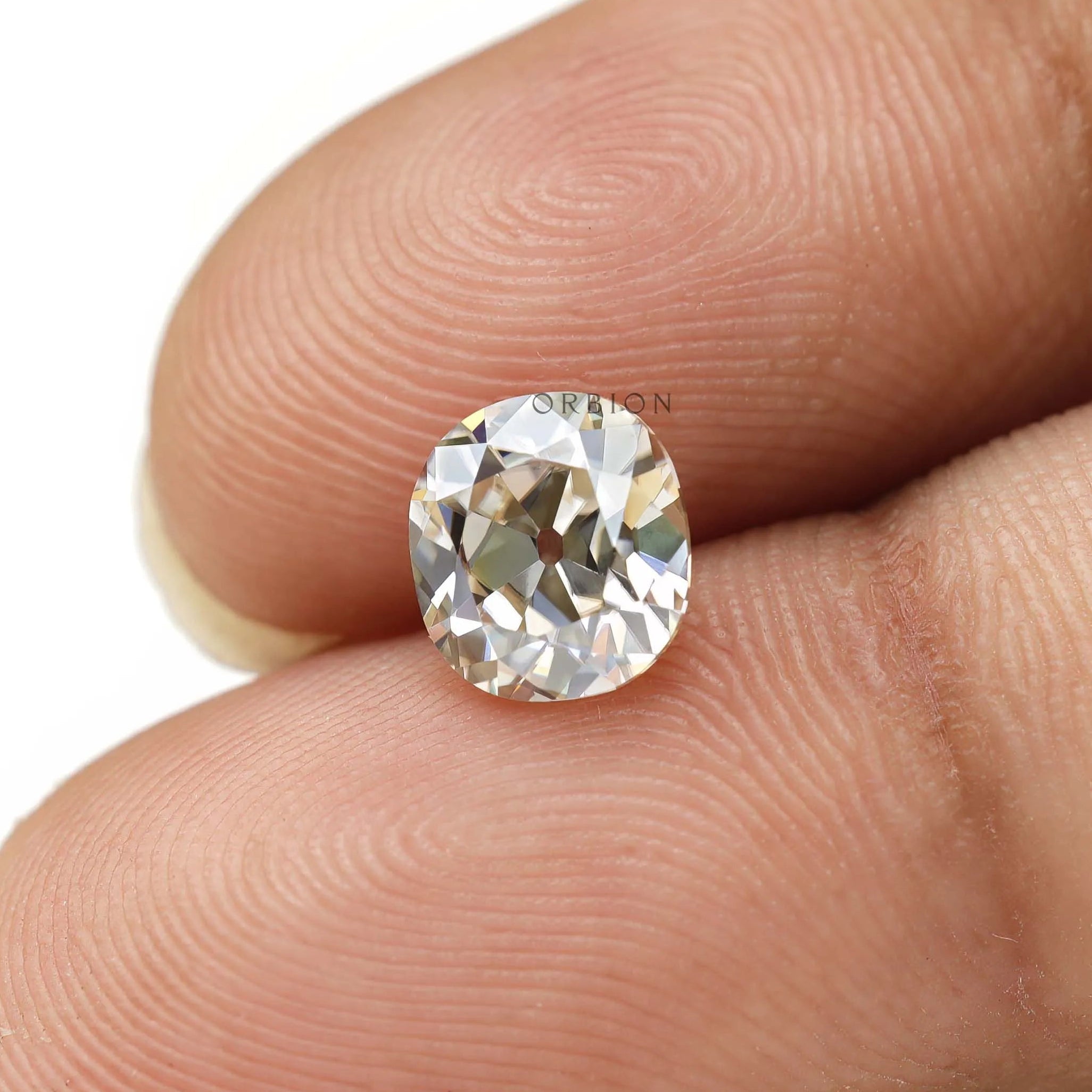 GHI elongated cushion old mine cut moissanite on fingertips