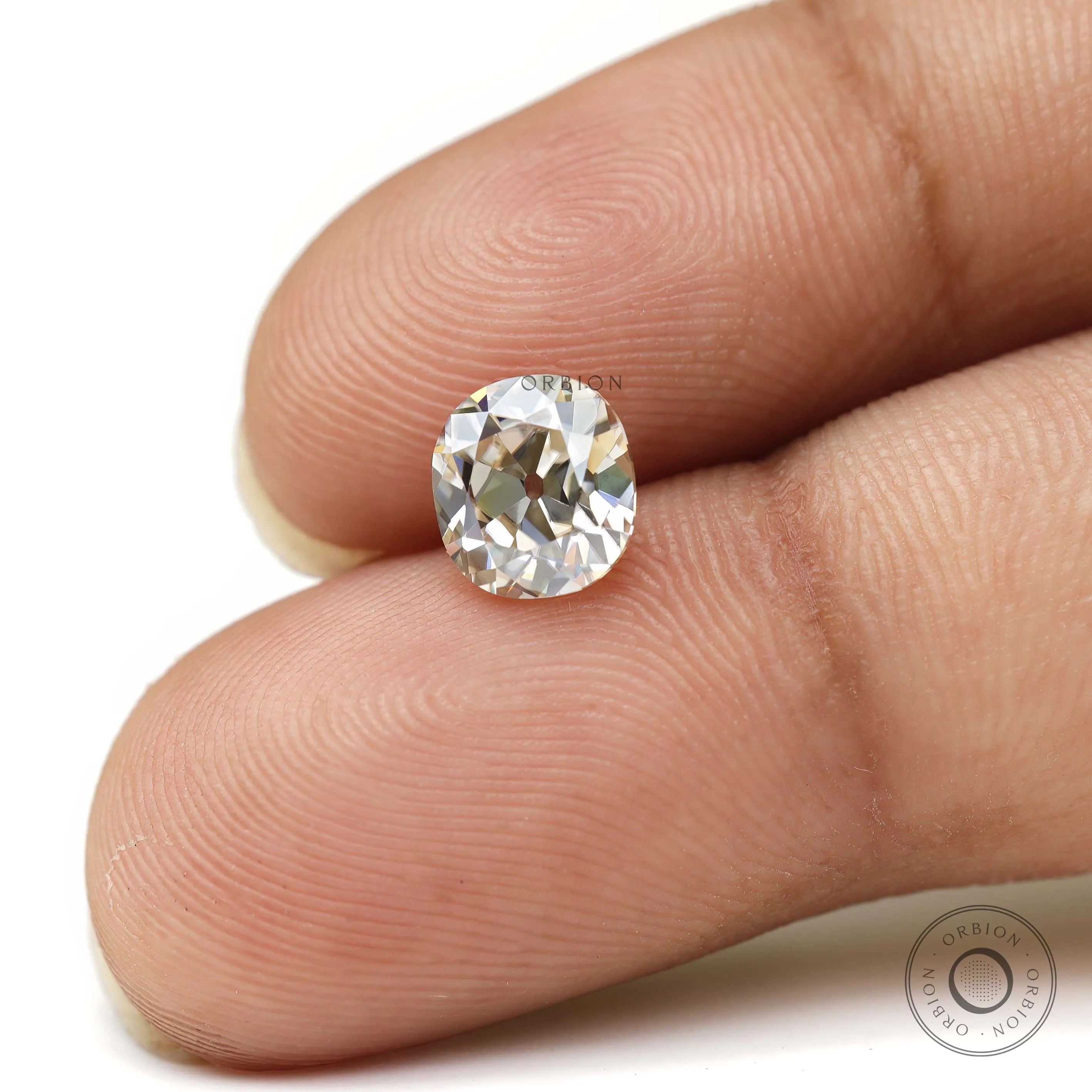 GHI elongated cushion old mine cut moissanite on fingertips