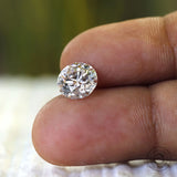Loose round colorless diamond shown on fingertips close up