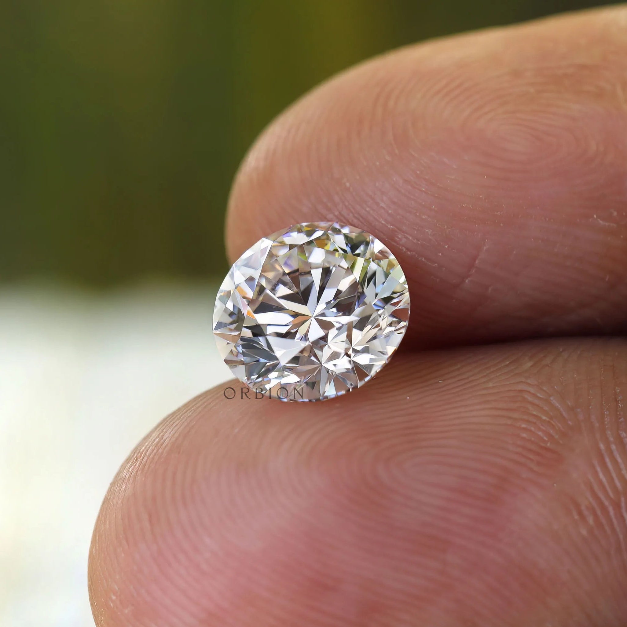 Loose round colorless diamond shown on fingertips close up