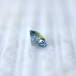 Macro fingertip view of fancy intense blue round diamond