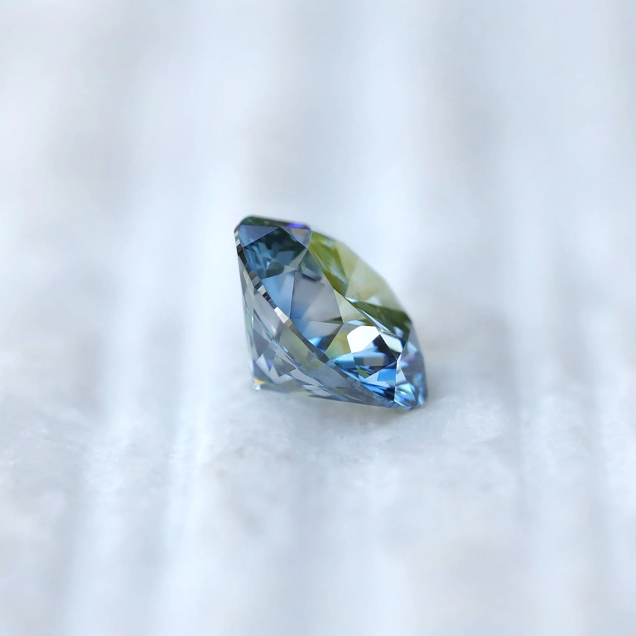 Macro fingertip view of fancy intense blue round diamond