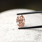 Oval pink lab grown diamond upright on stone surface