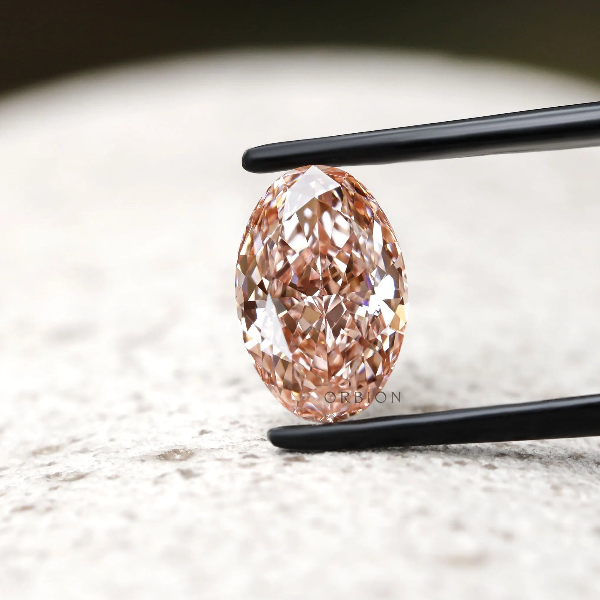 Oval pink lab grown diamond upright on stone surface