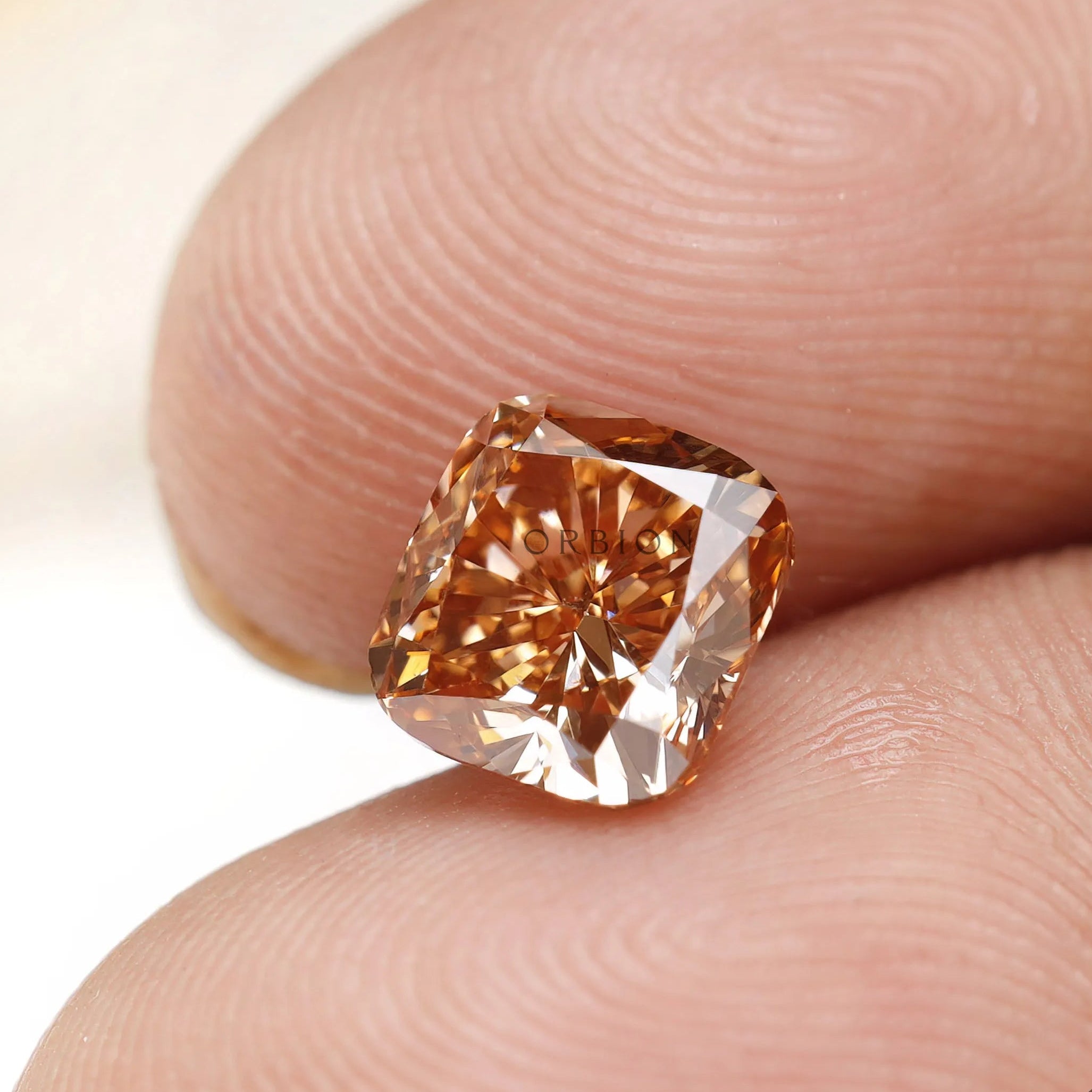Fancy orange cushion lab diamond displayed on fingertips