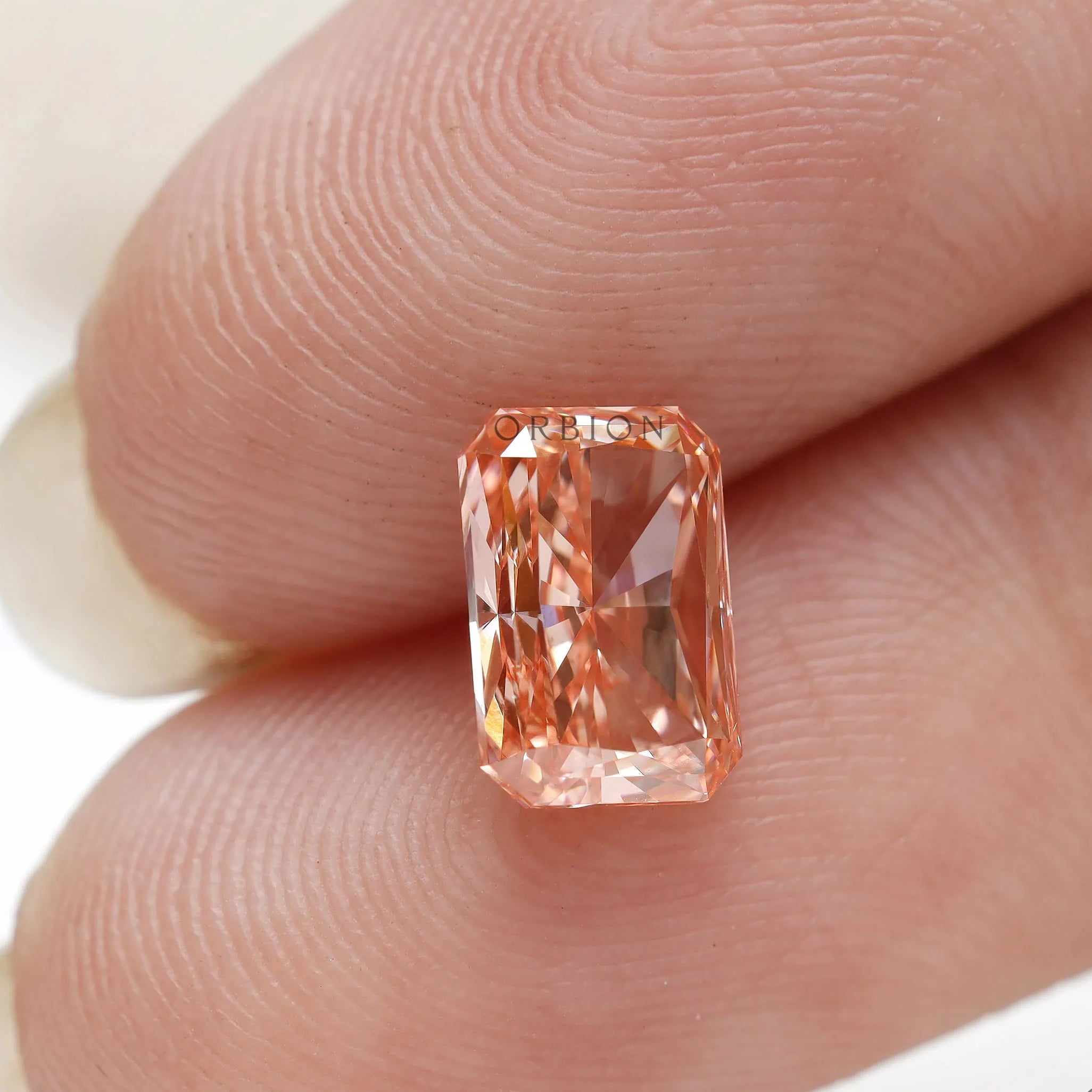 Vertical fingertip view of radiant cut fancy pink diamond