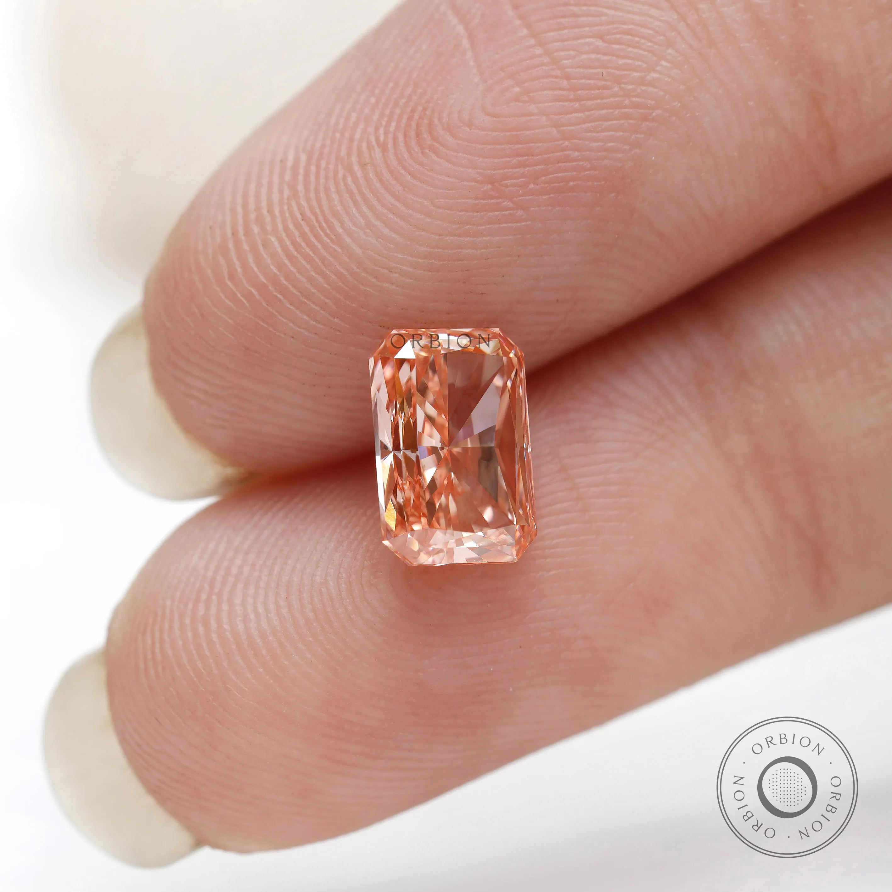 Vertical fingertip view of radiant cut fancy pink diamond