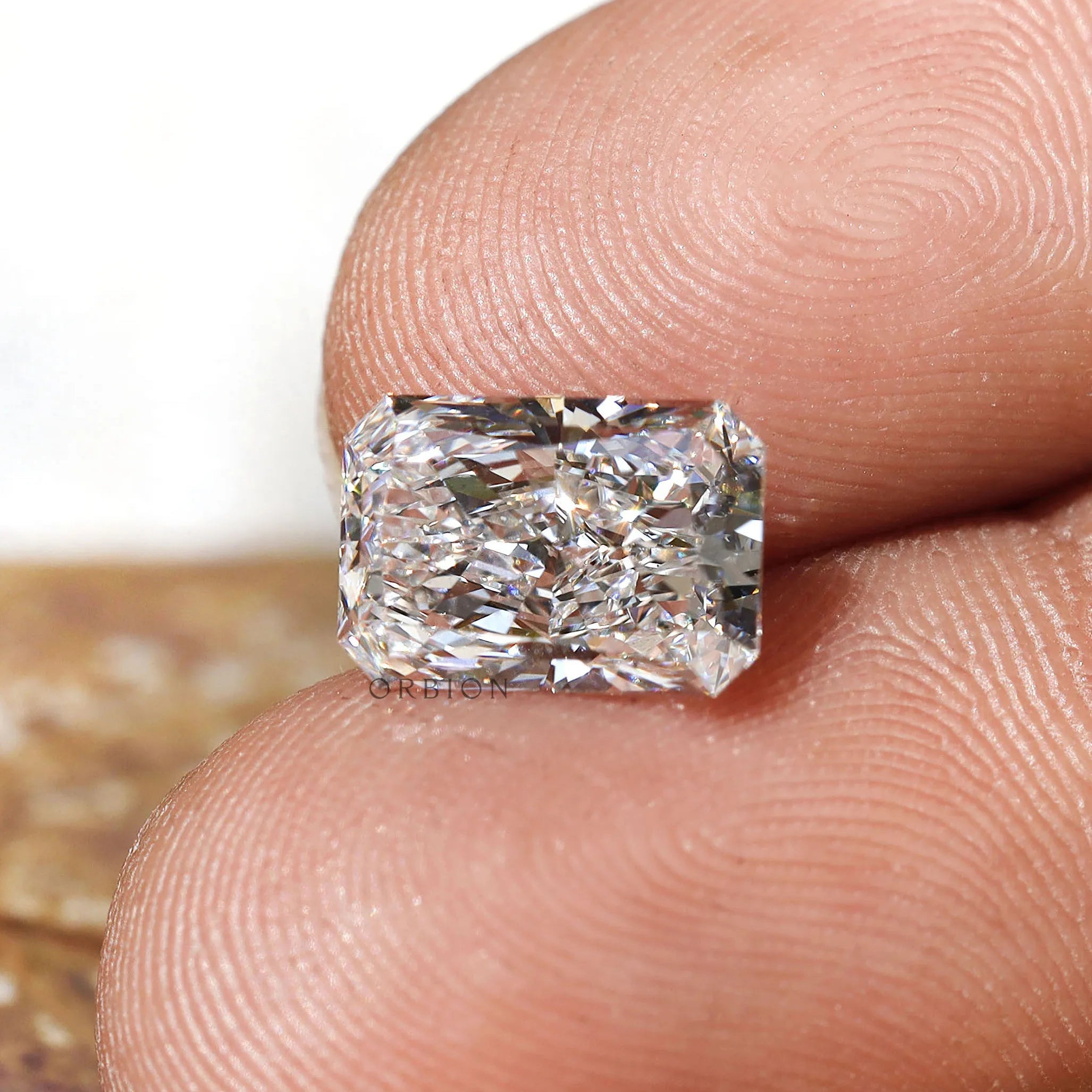 Horizontal fingertip view of radiant brilliant loose diamond