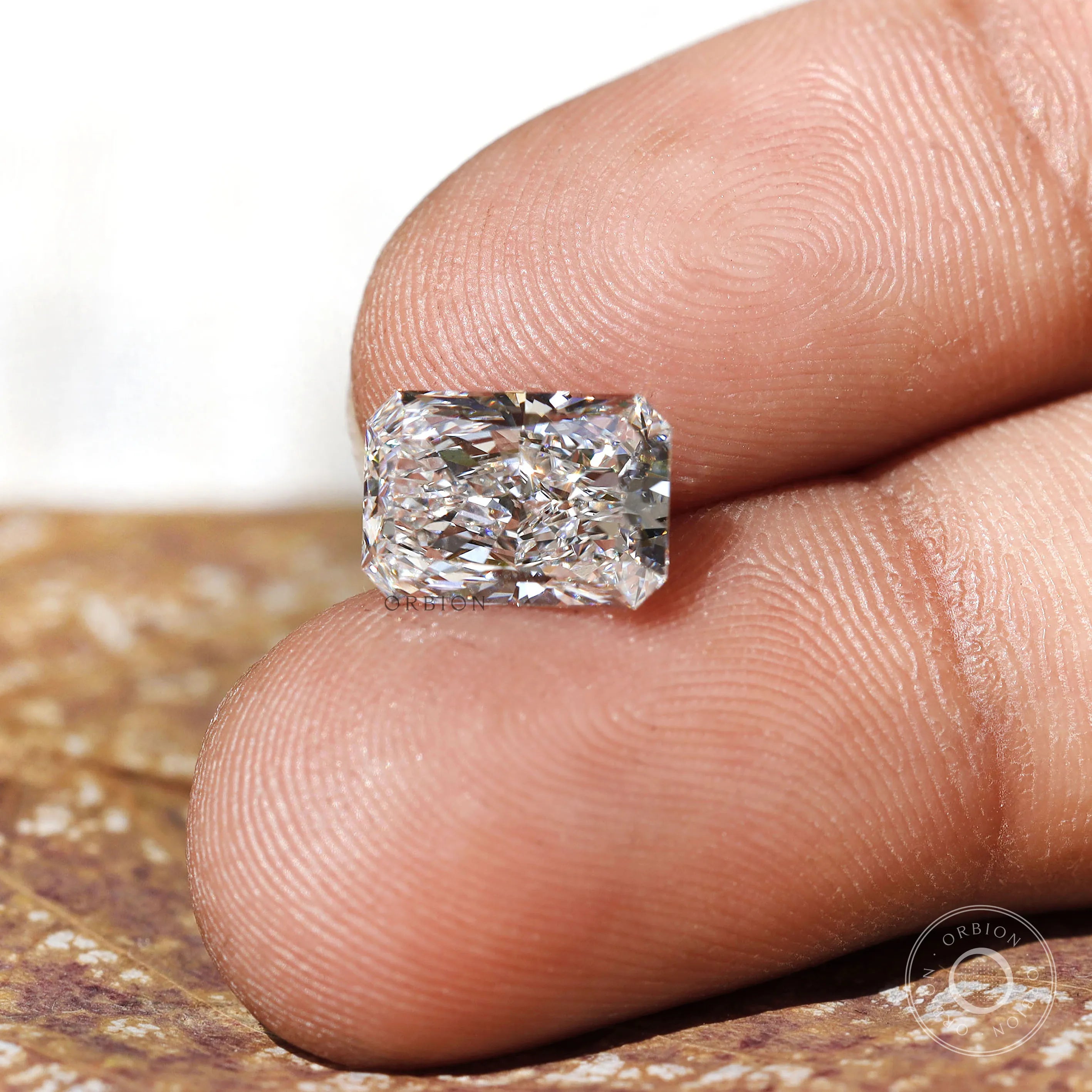 Horizontal fingertip view of radiant brilliant loose diamond