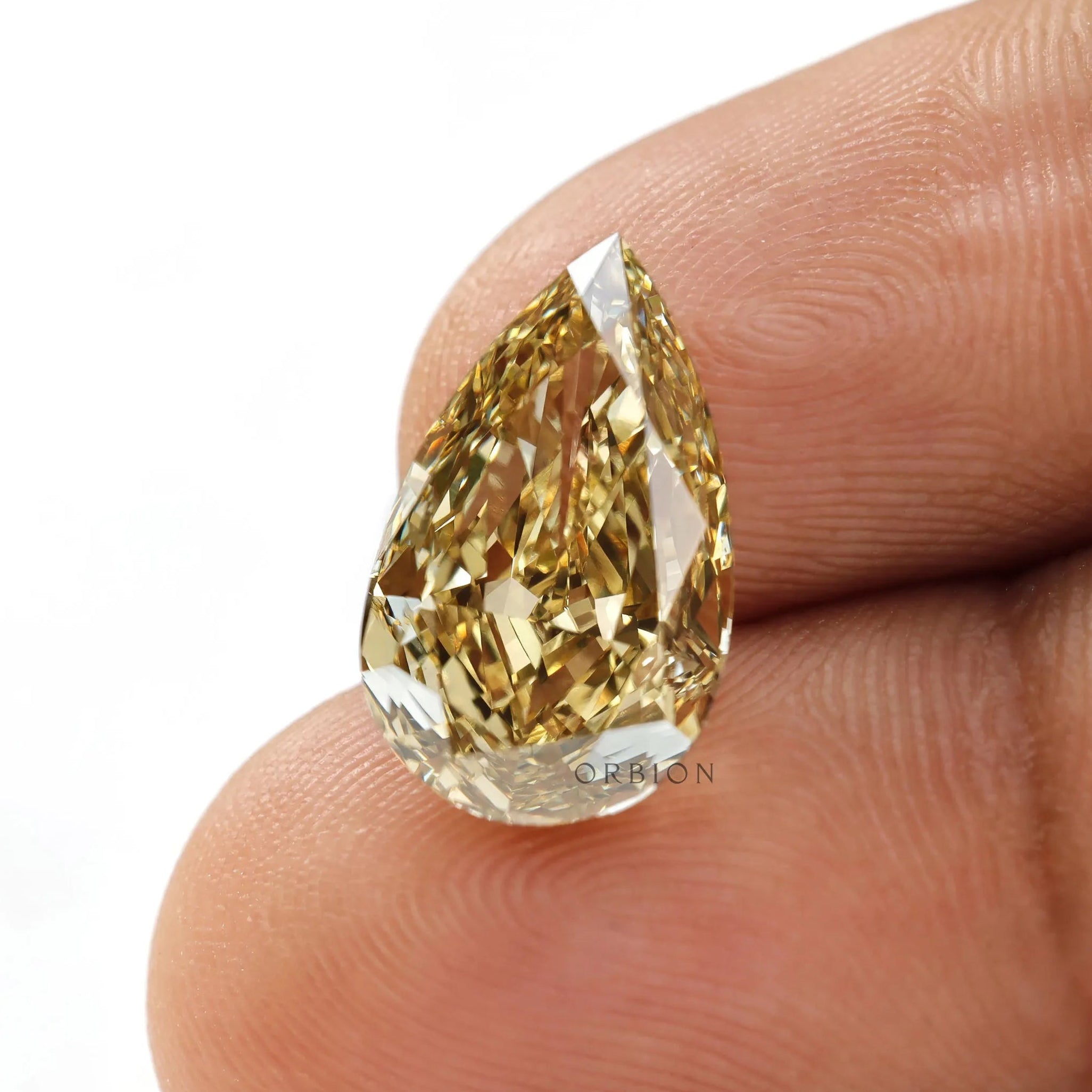 Close fingertip view of fancy intense yellow pear diamond
