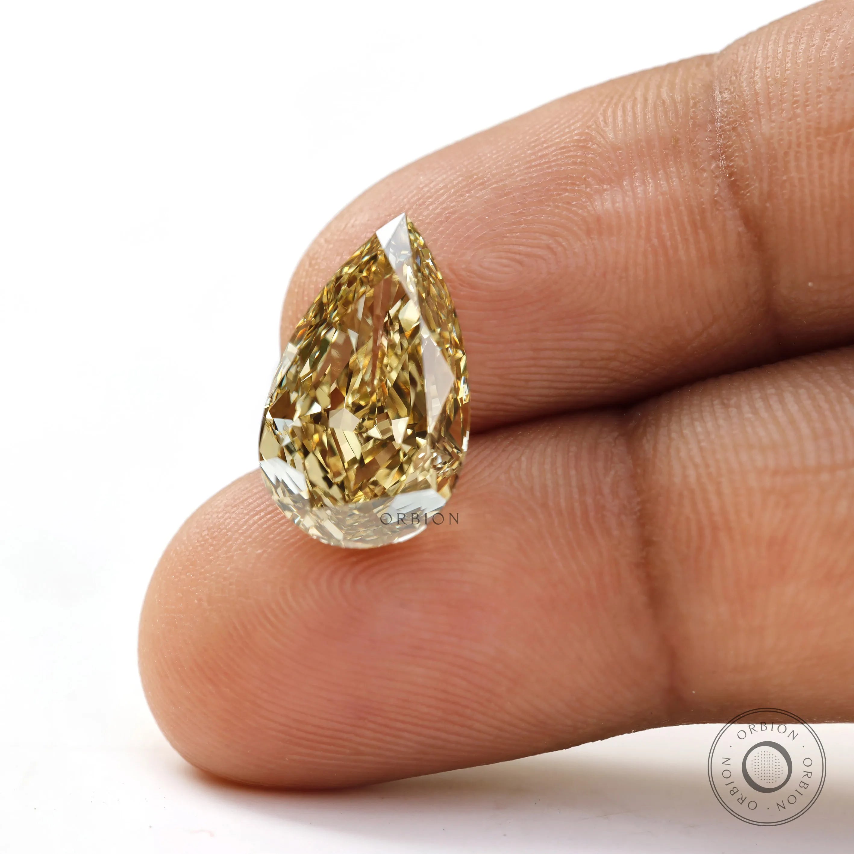 Close fingertip view of fancy intense yellow pear diamond