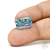 Fancy vivid blue radiant diamond displayed on fingertip closeup