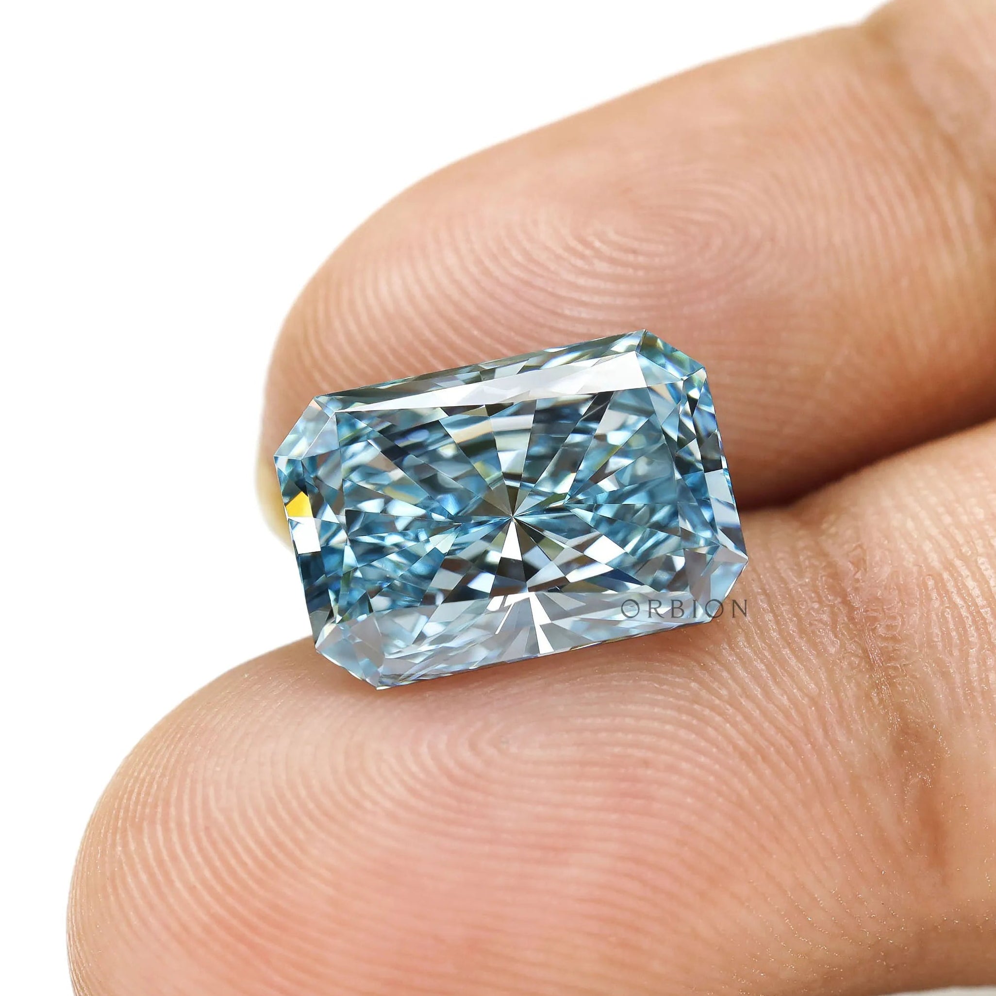 Fancy vivid blue radiant diamond displayed on fingertip closeup
