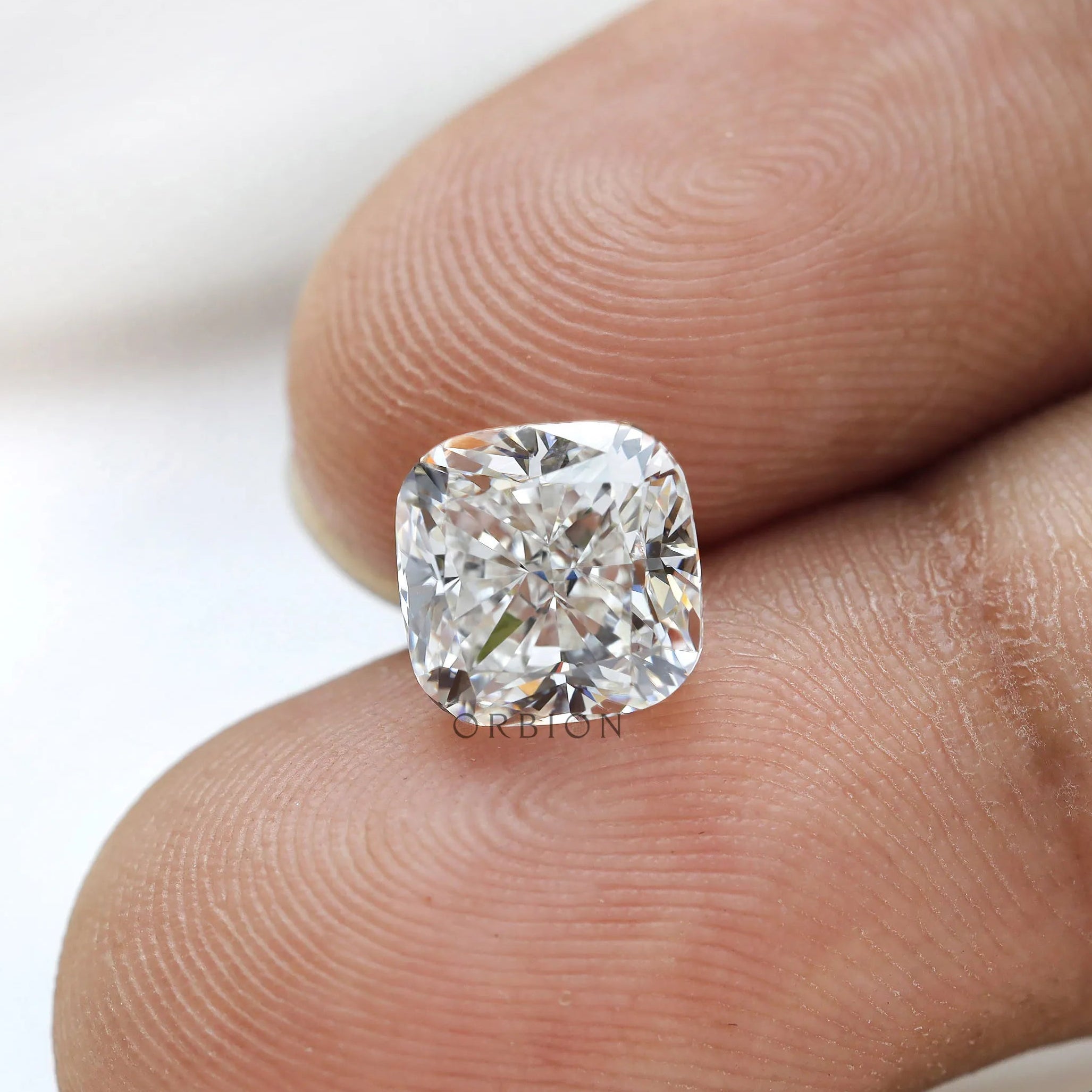 Macro fingertip view of cushion brilliant loose lab diamond