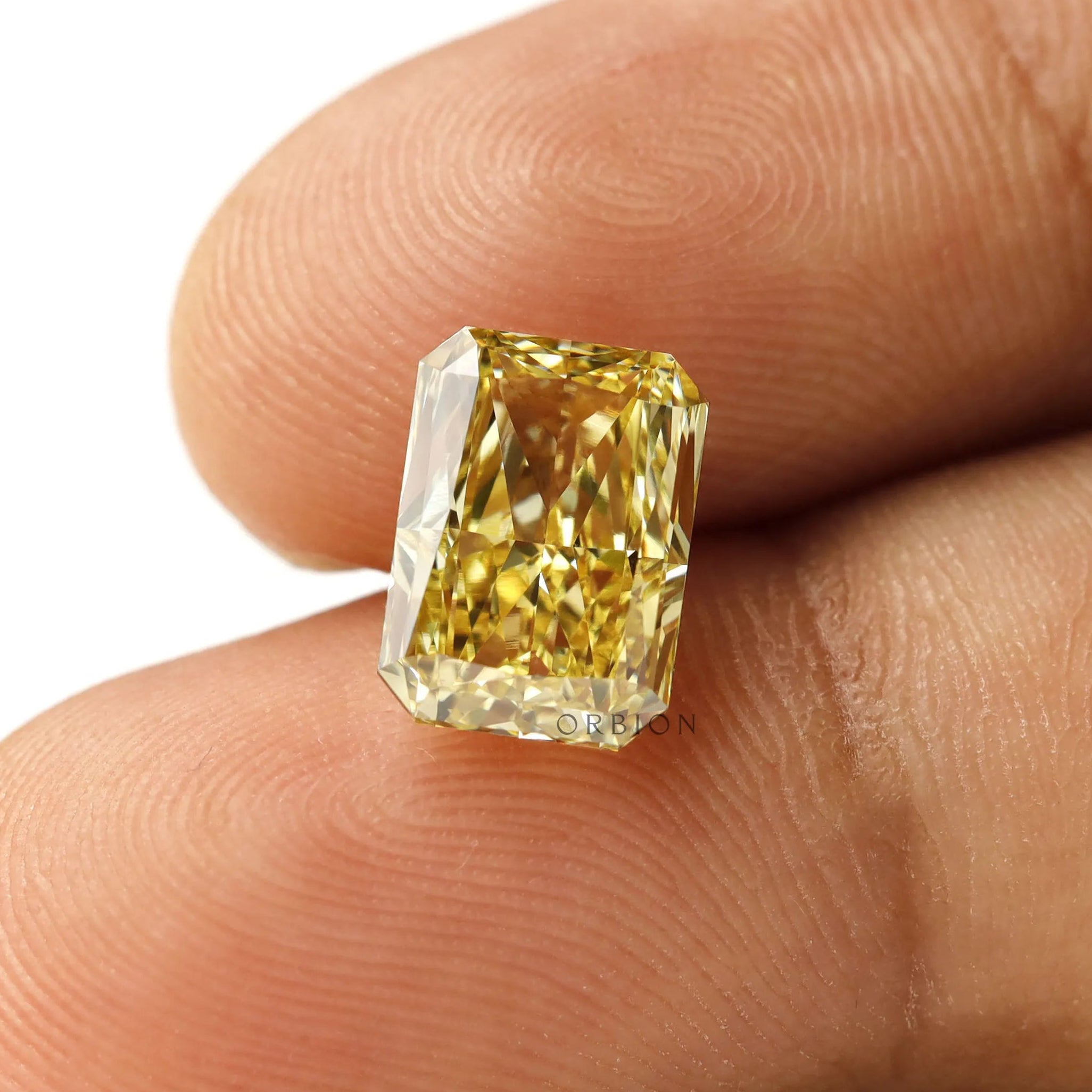Fancy intense yellow radiant lab diamond shown on fingertip
