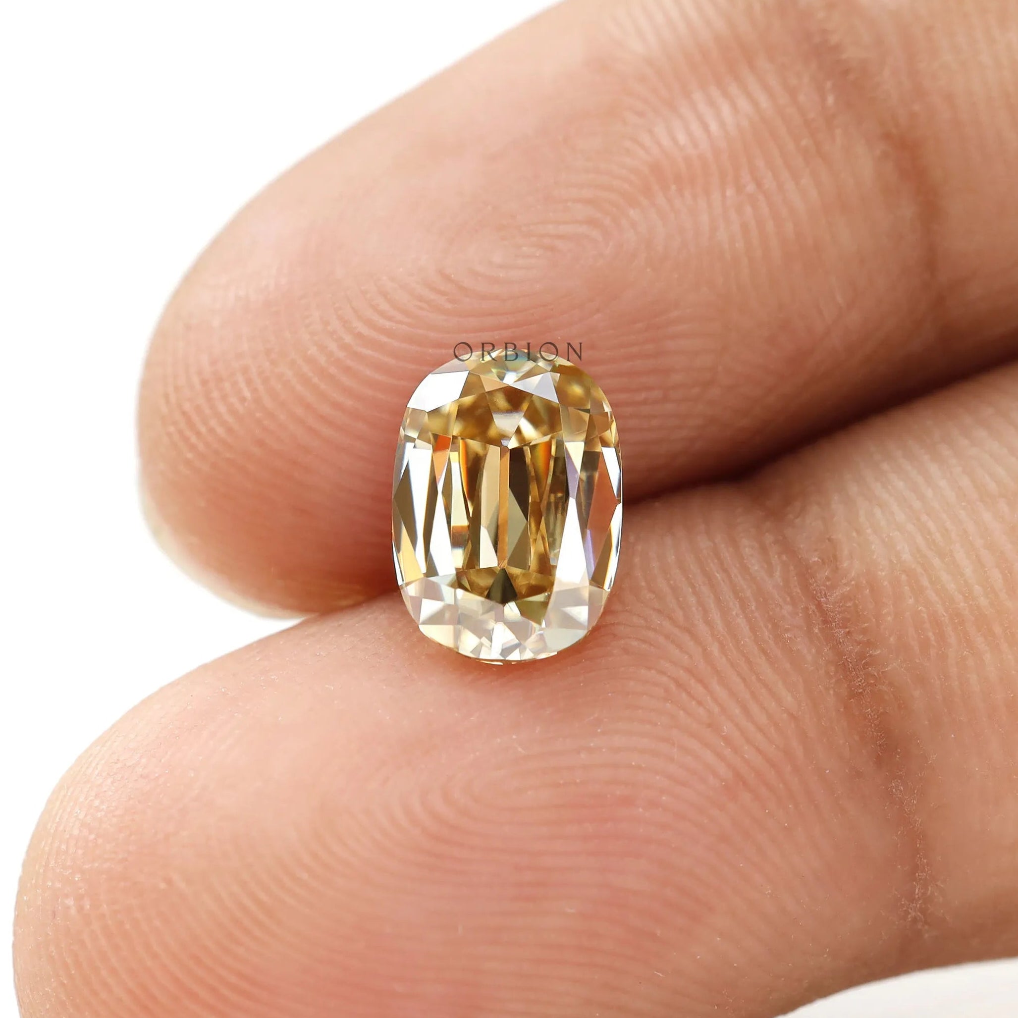 Elongated cushion old mine moissanite angled between two fingers