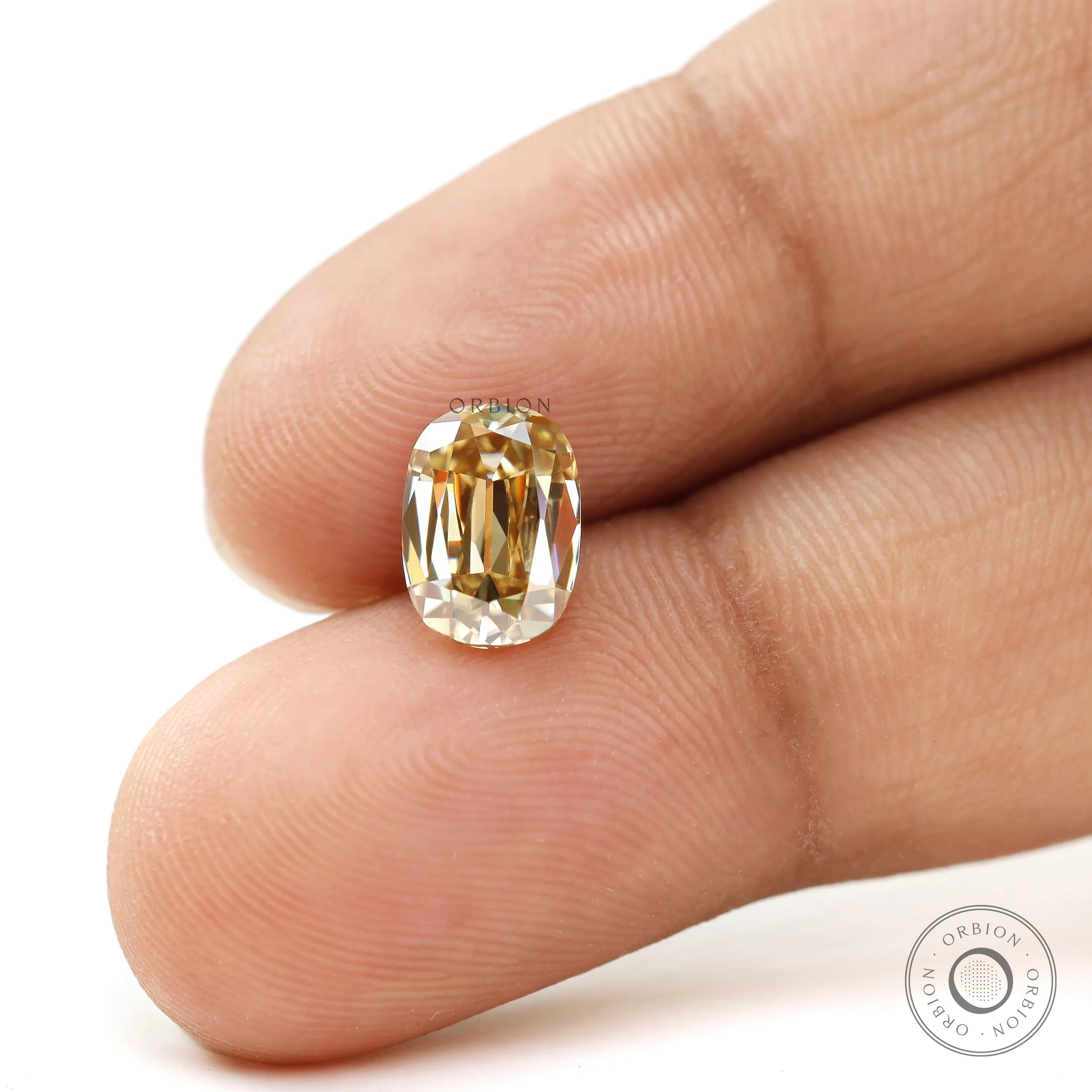 Elongated cushion old mine moissanite angled between two fingers