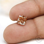 Close fingertip view of fancy orange cushion lab diamond