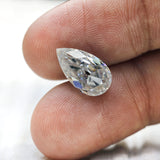 Pear loose moissanite placed on fingertips for size