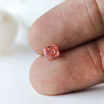 Vivid pink cushion lab diamond displayed on fingertip