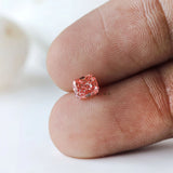 Vivid pink cushion lab diamond displayed on fingertip