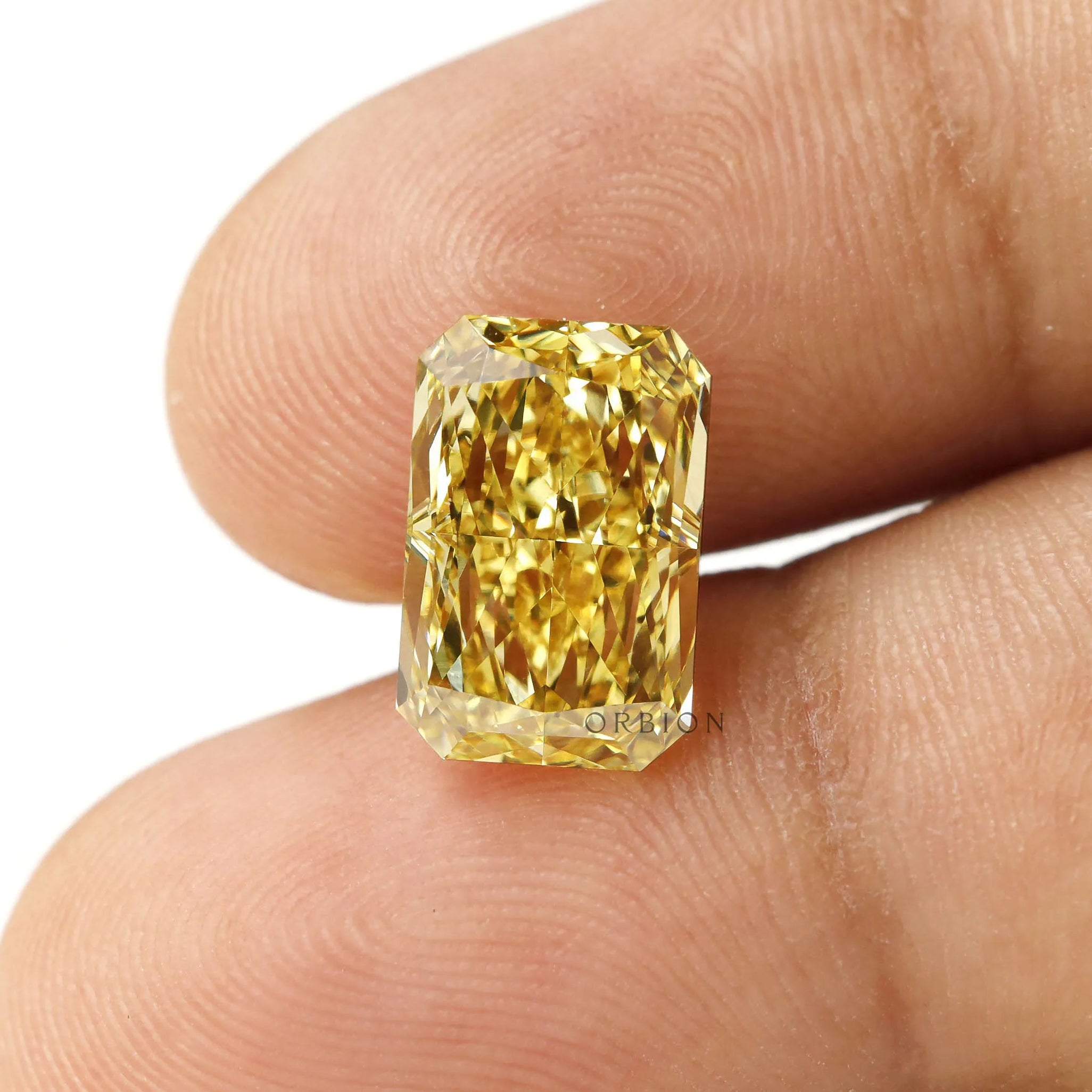 Fancy vivid yellow radiant lab diamond shown on fingertip