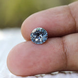 Close fingertip shot of round brilliant blue loose diamond