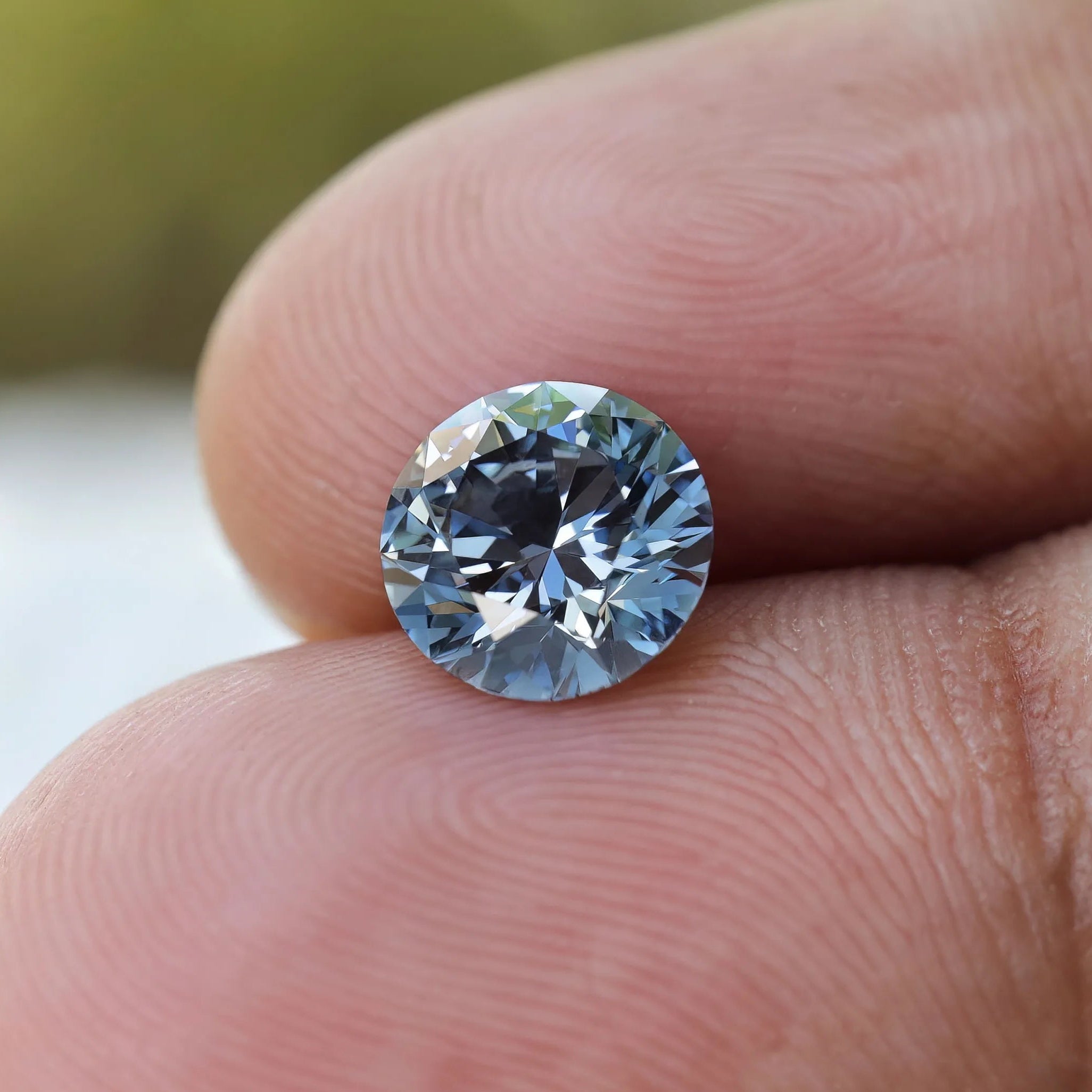 Close fingertip shot of round brilliant blue loose diamond