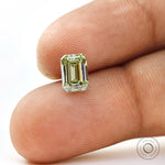 Fancy green emerald lab diamond shown on fingertip