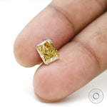 Radiant brilliant cut fancy yellow lab diamond on fingertips