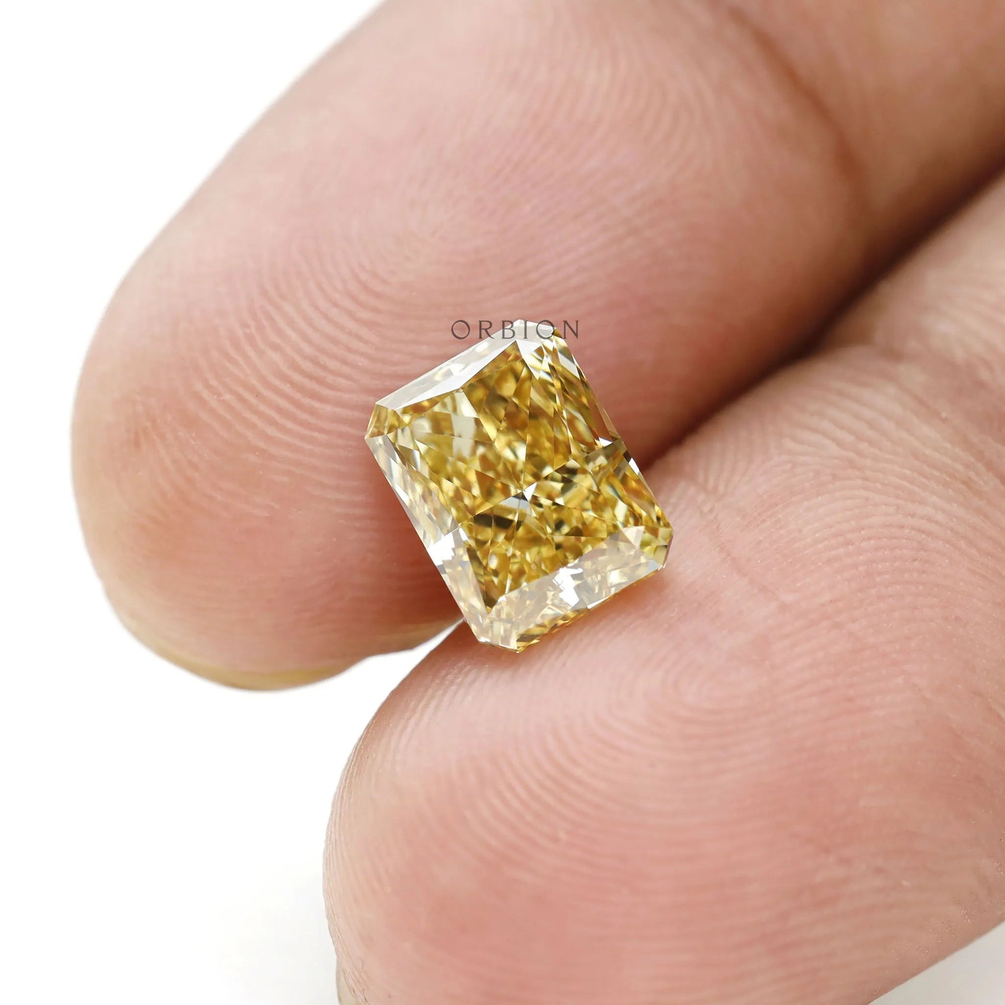 Radiant brilliant cut fancy yellow lab diamond on fingertips