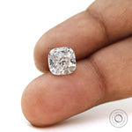 Cushion brilliant loose moissanite displayed on fingertips close-up