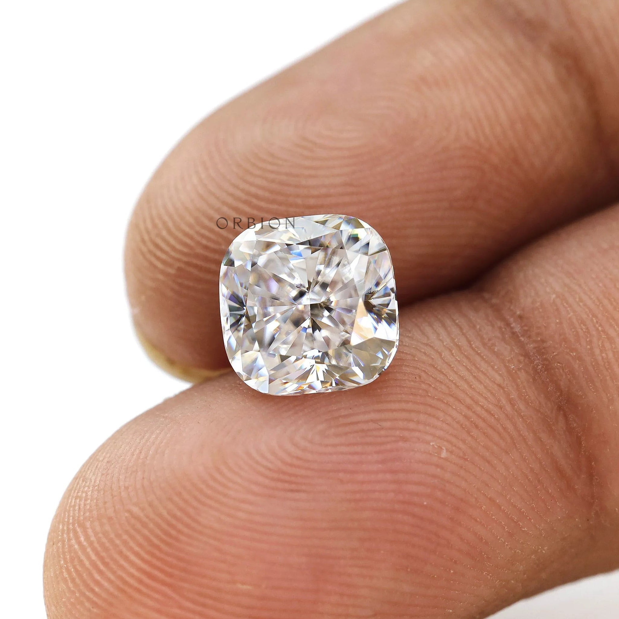 Cushion brilliant loose moissanite displayed on fingertips close-up