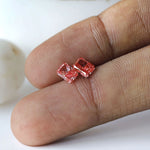 Macro fingertip view of vivid pink radiant diamond pair