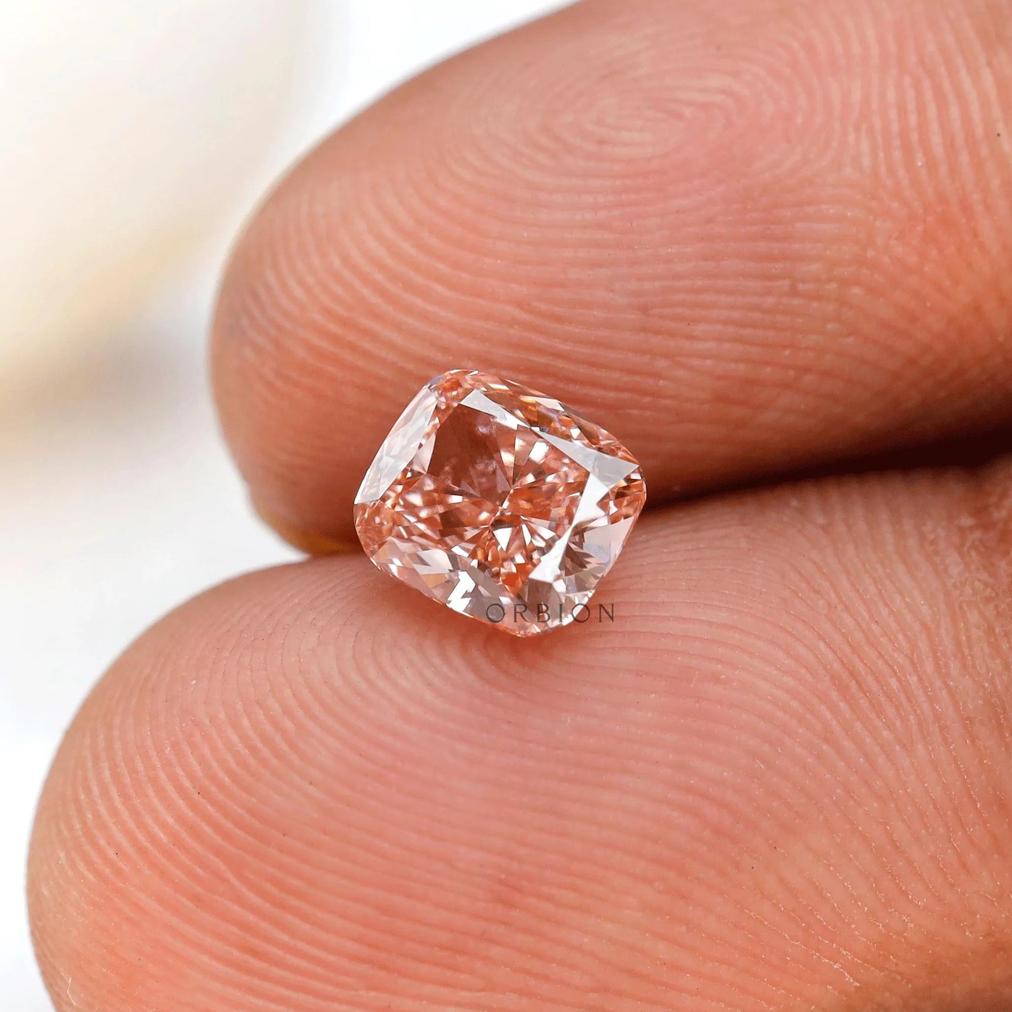 Close fingertip view of fancy pink elongated cushion diamond