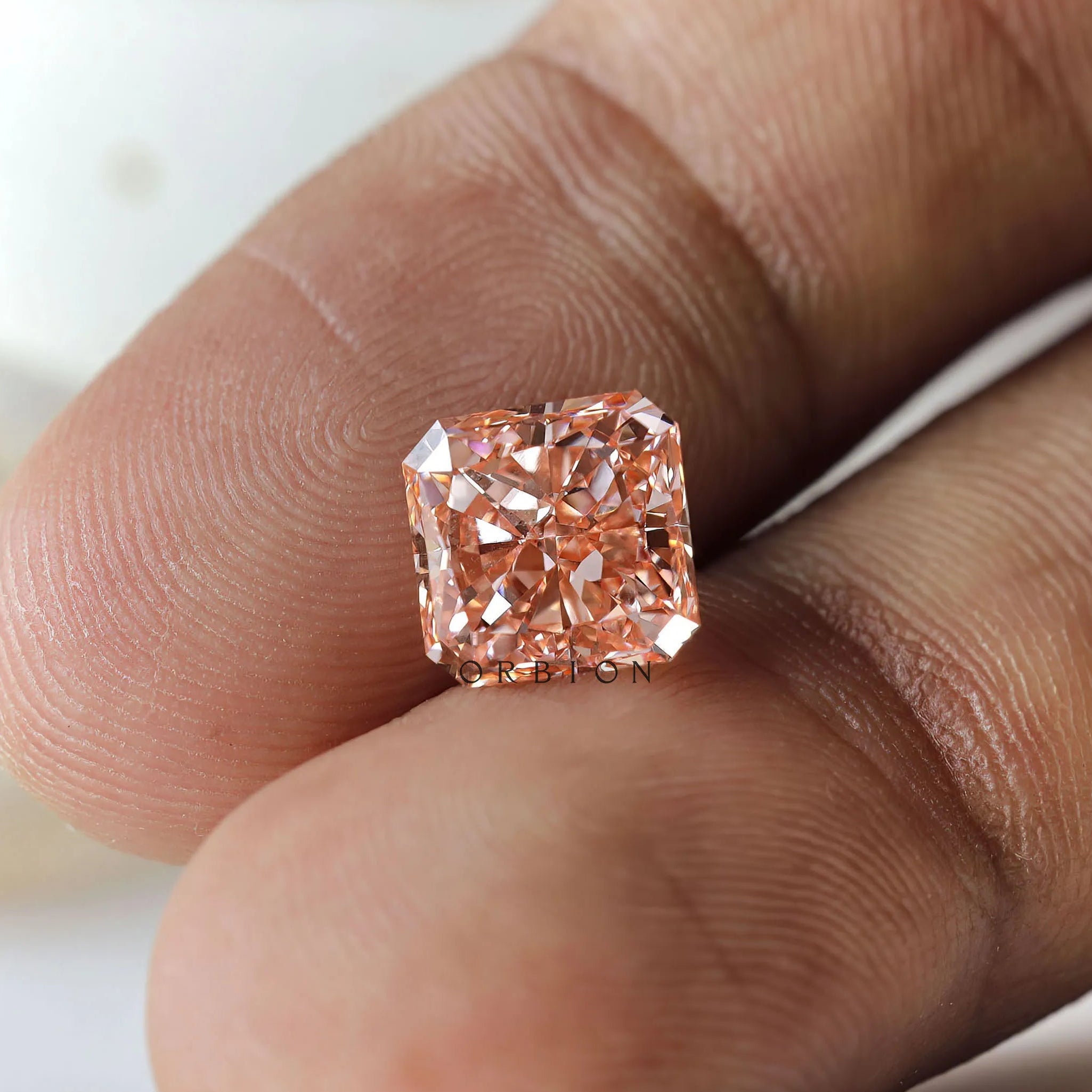 Macro fingertip view of radiant brilliant fancy vivid pink diamond