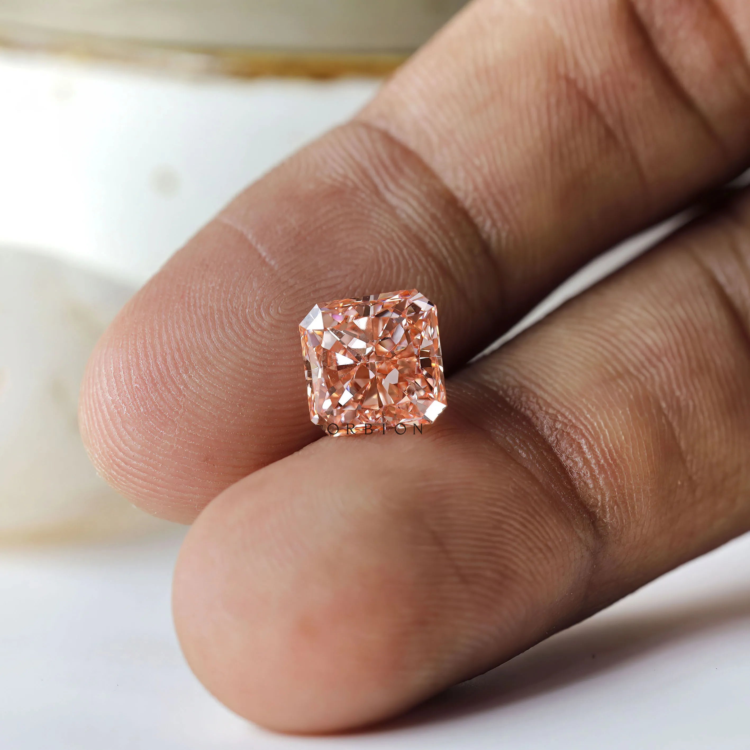 Macro fingertip view of radiant brilliant fancy vivid pink diamond