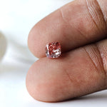 Fancy deep purplish pink cushion diamond shown on fingertip