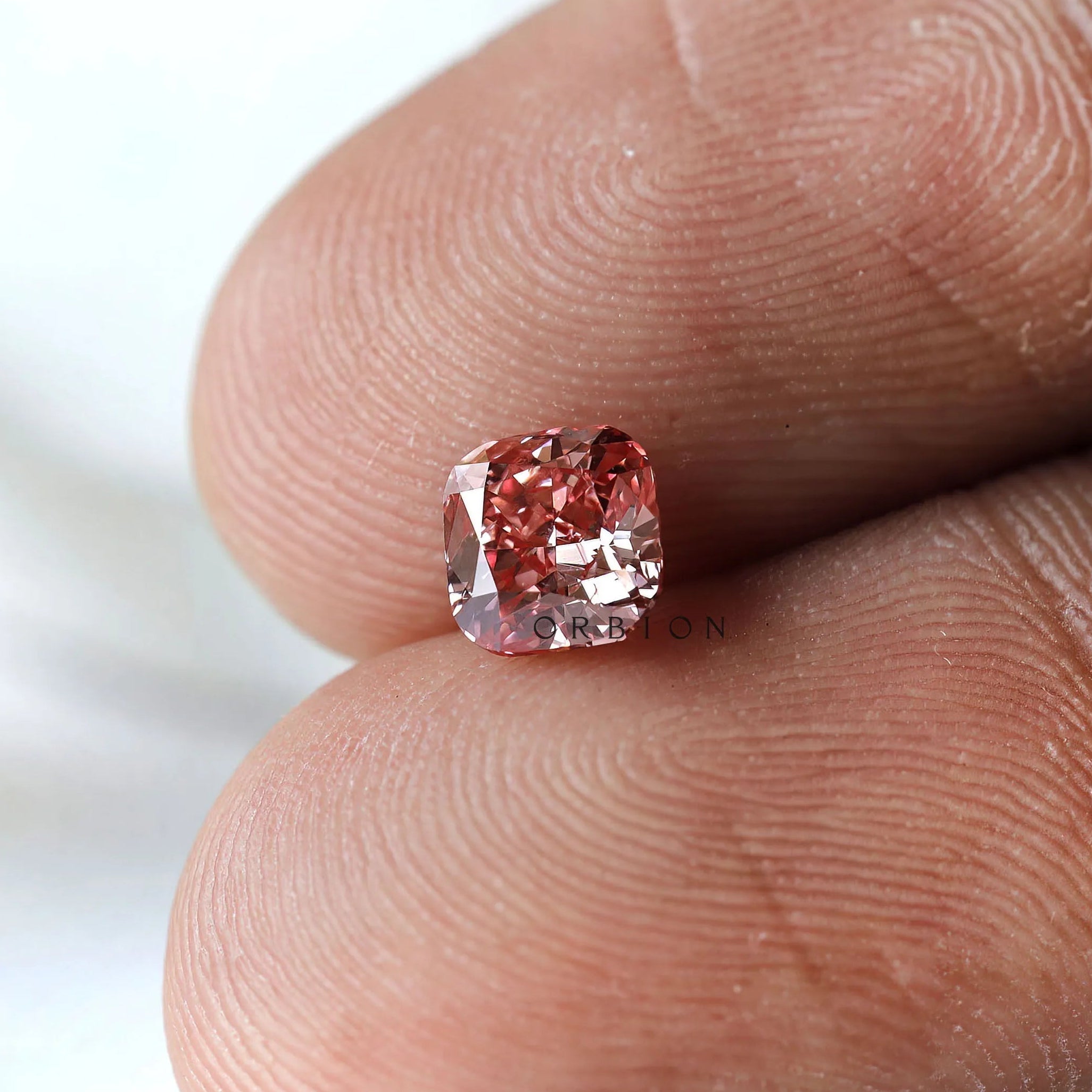 Fancy deep purplish pink cushion diamond shown on fingertip