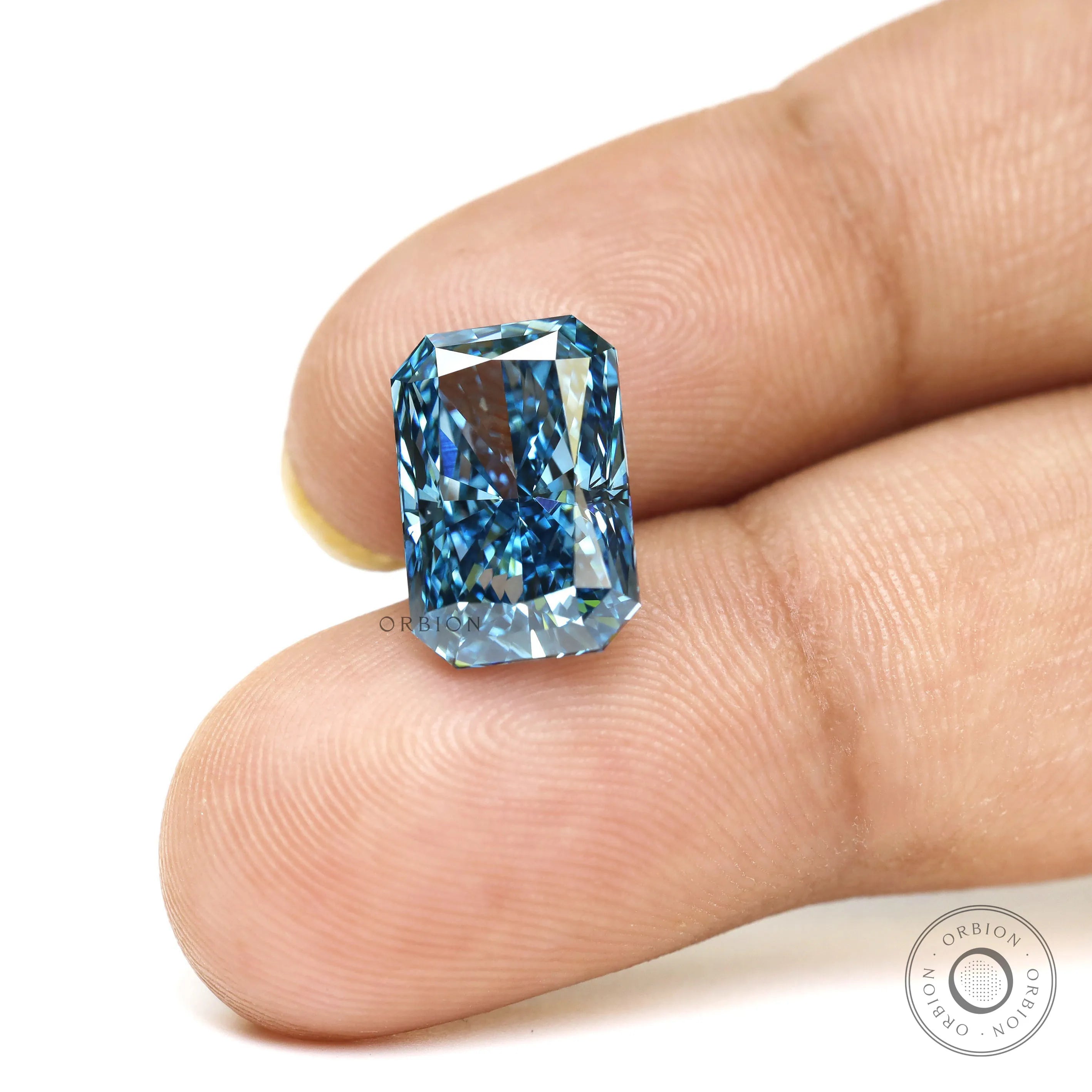Fancy vivid blue radiant lab diamond shown on fingertips