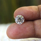 Brilliant cut round lab diamond held on fingertips