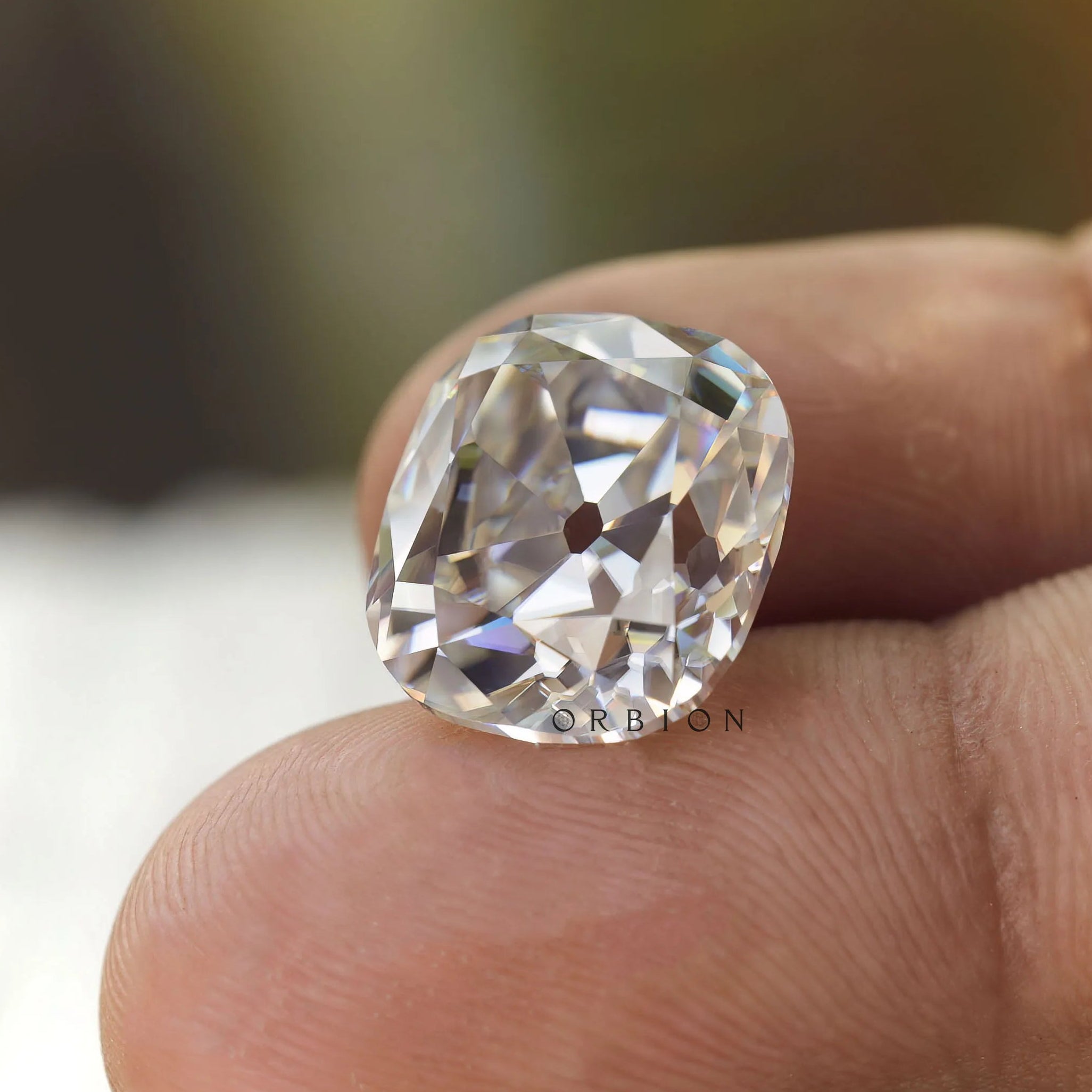 Large elongated cushion moissanite displayed on fingertip closeup