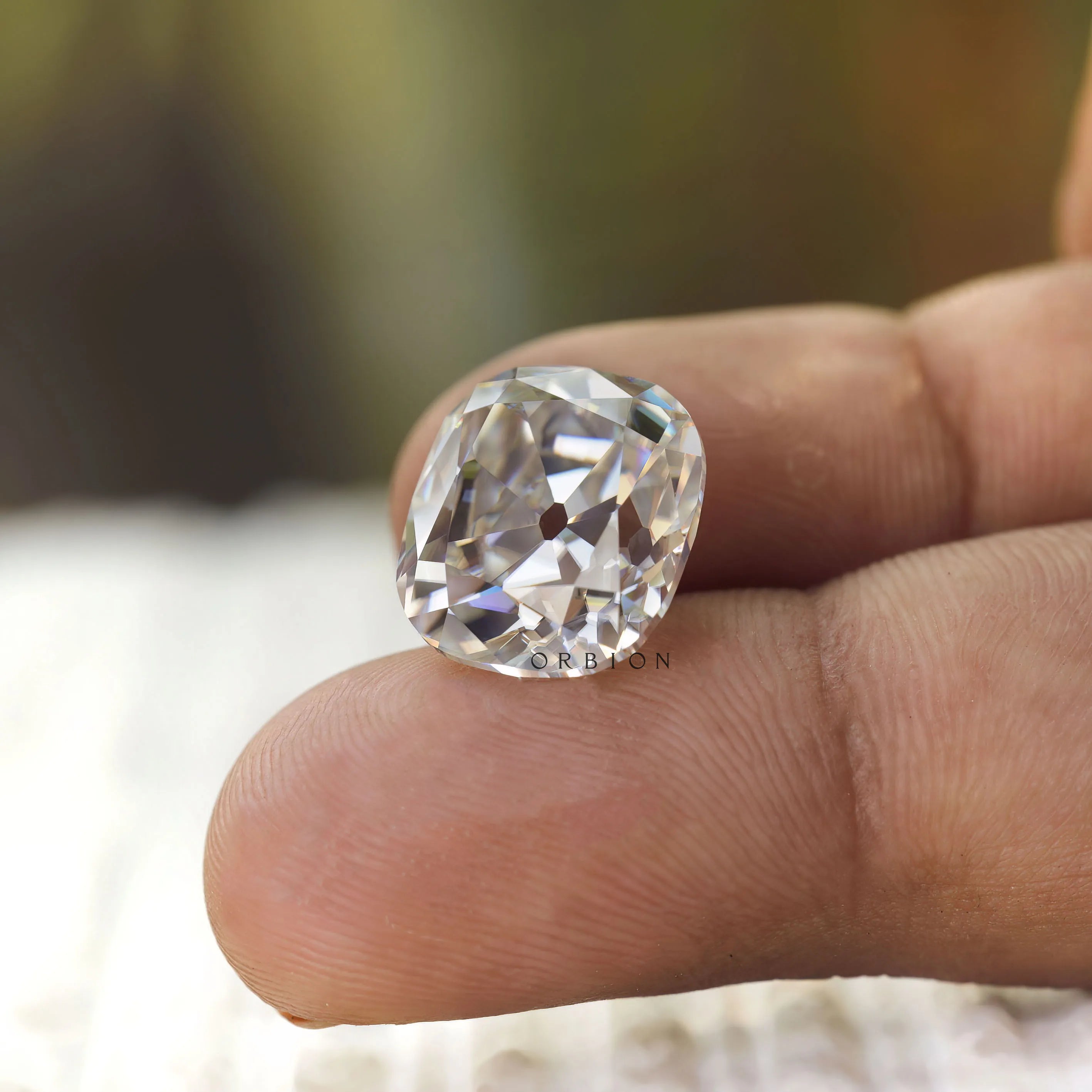 Large elongated cushion moissanite displayed on fingertip closeup