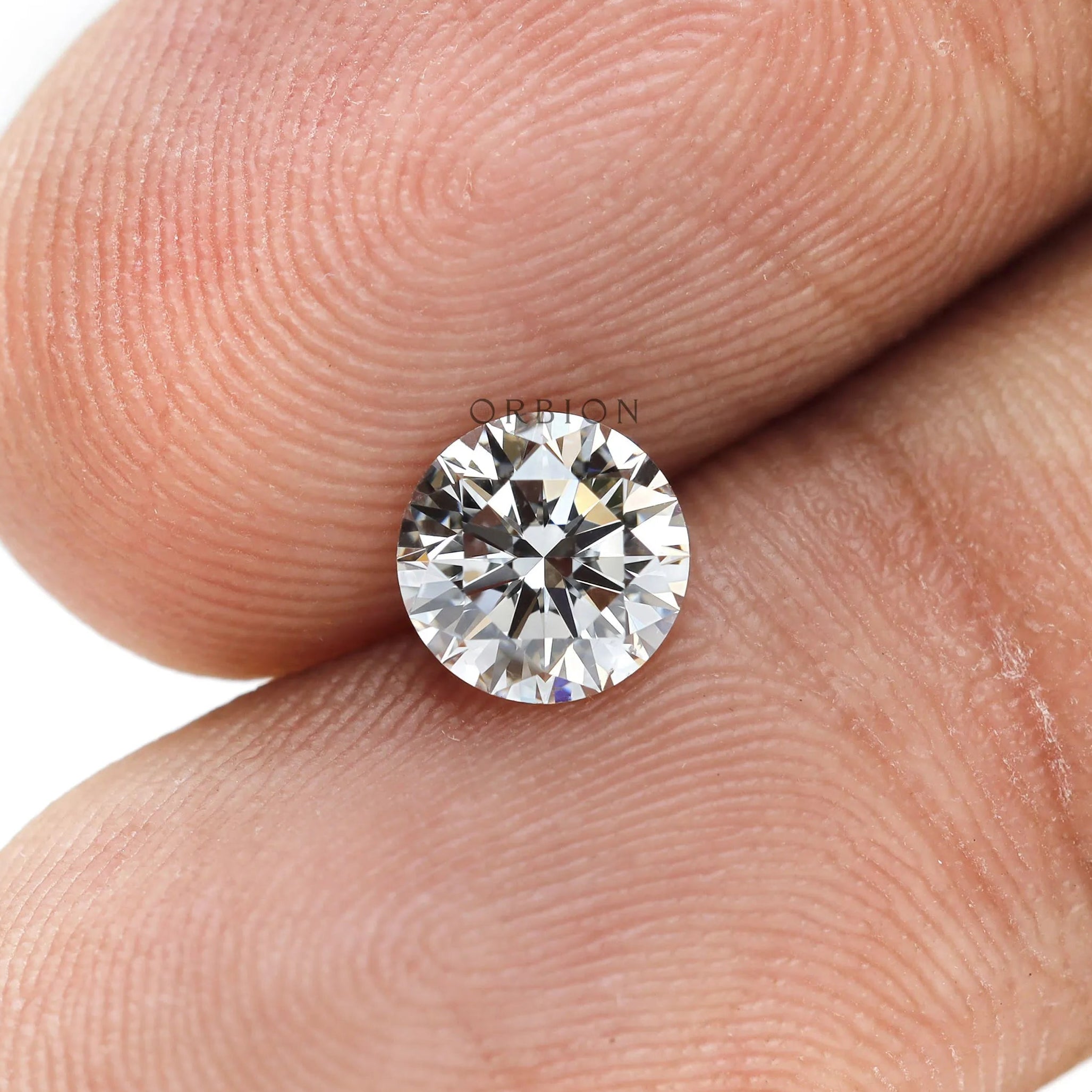 Macro fingertip view of round brilliant loose lab diamond