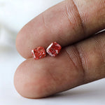 Close fingertip view of matching vivid pink lab diamonds