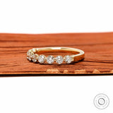 Angled front view of round lab diamond shared prong half eternity wedding band