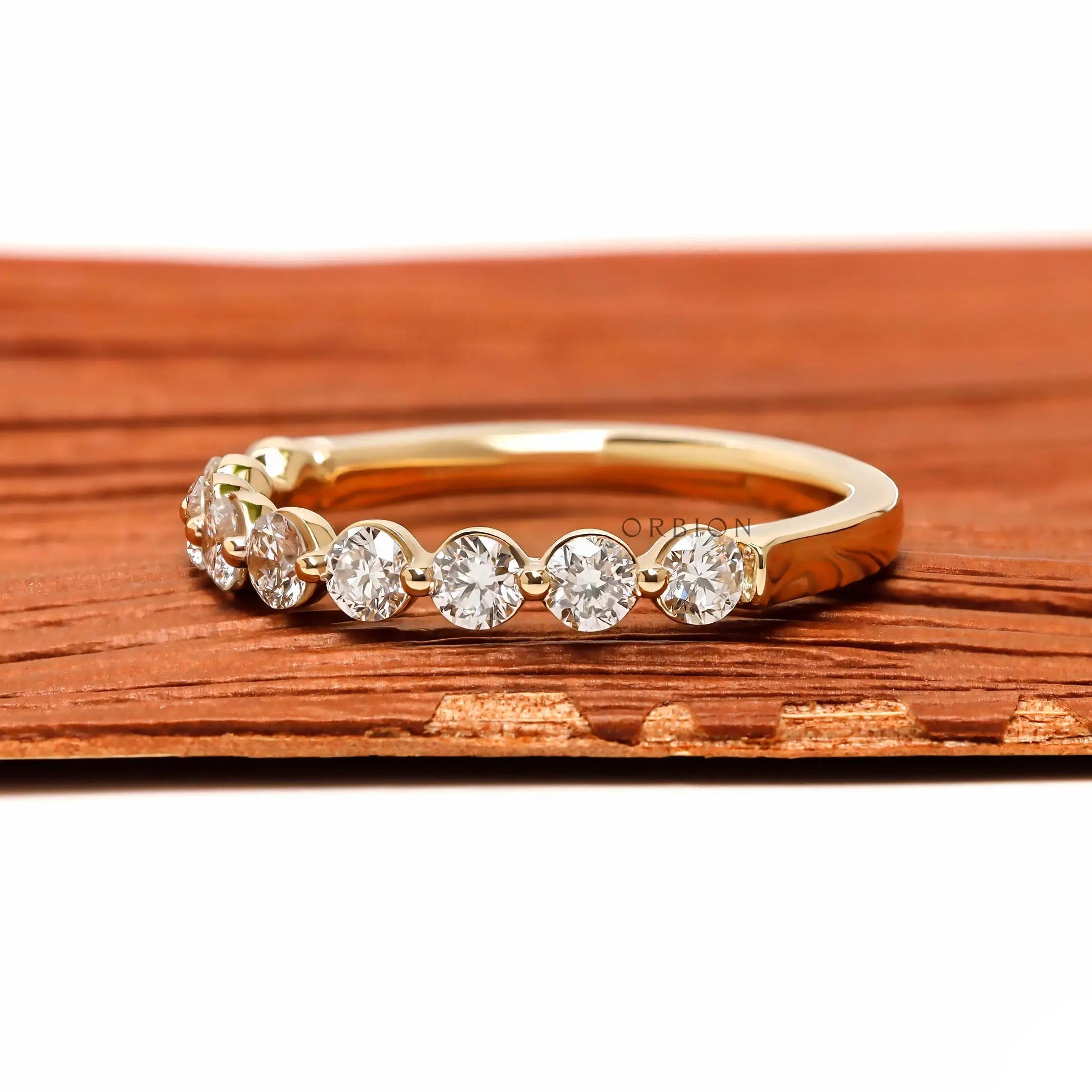 Angled front view of round lab diamond shared prong half eternity wedding band