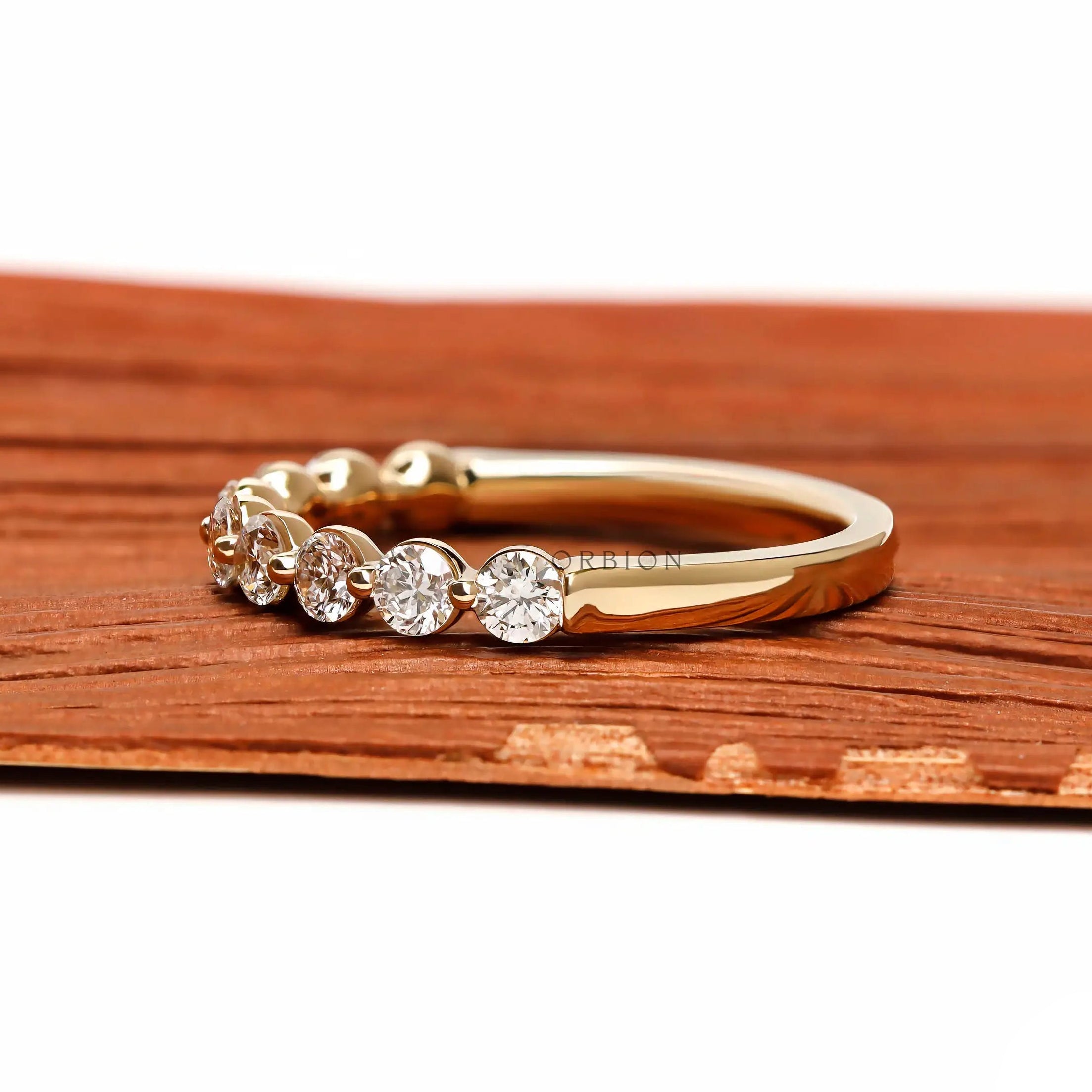 Side profile view of round lab diamond shared prong half eternity wedding band