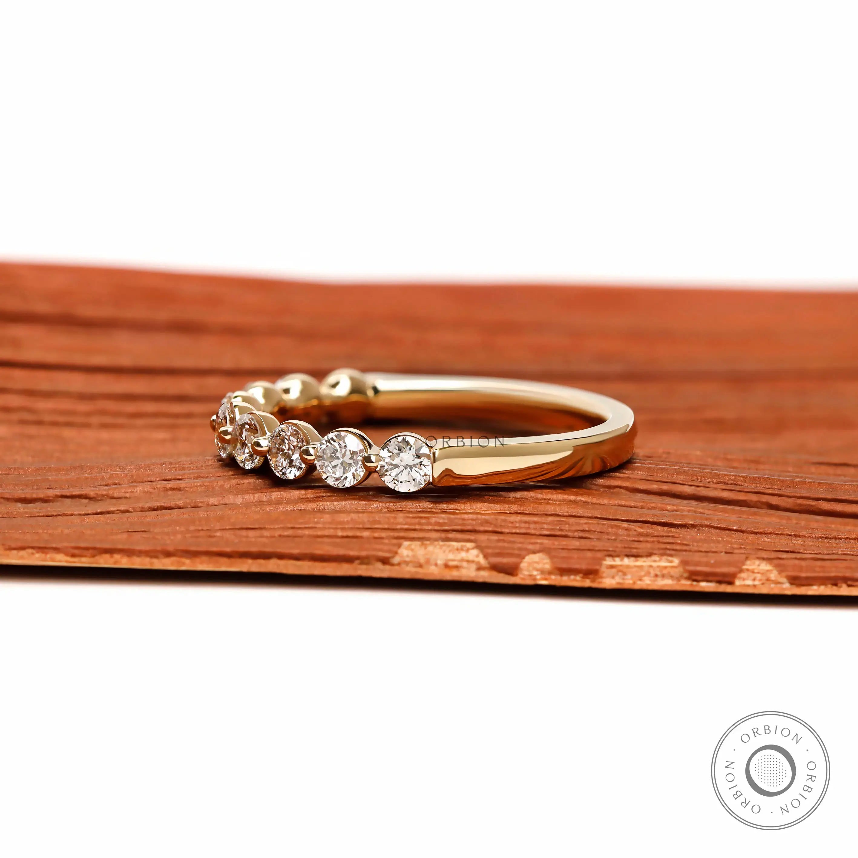 Side profile view of round lab diamond shared prong half eternity wedding band
